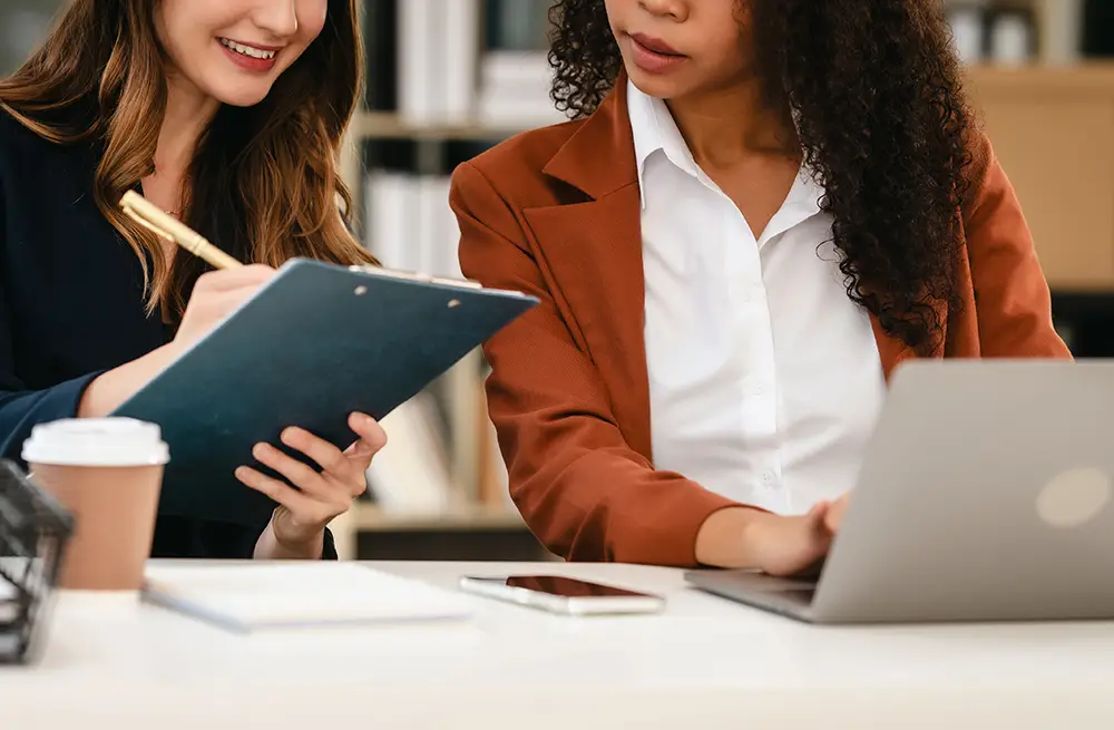 two professional women compare data in an office